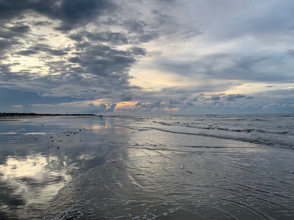 Piscinas de água transparente na maré baixa em Guajiru, com reflexo do céu na areia molhada